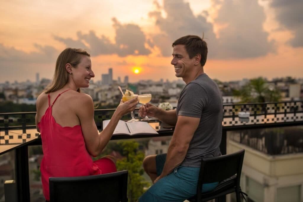 Two people sitting at a table with drinks, overlooking a cityscape at sunset.