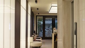 Un couloir moderne avec un ensemble de canapés, un comptoir d’accueil et une porte sur la droite.