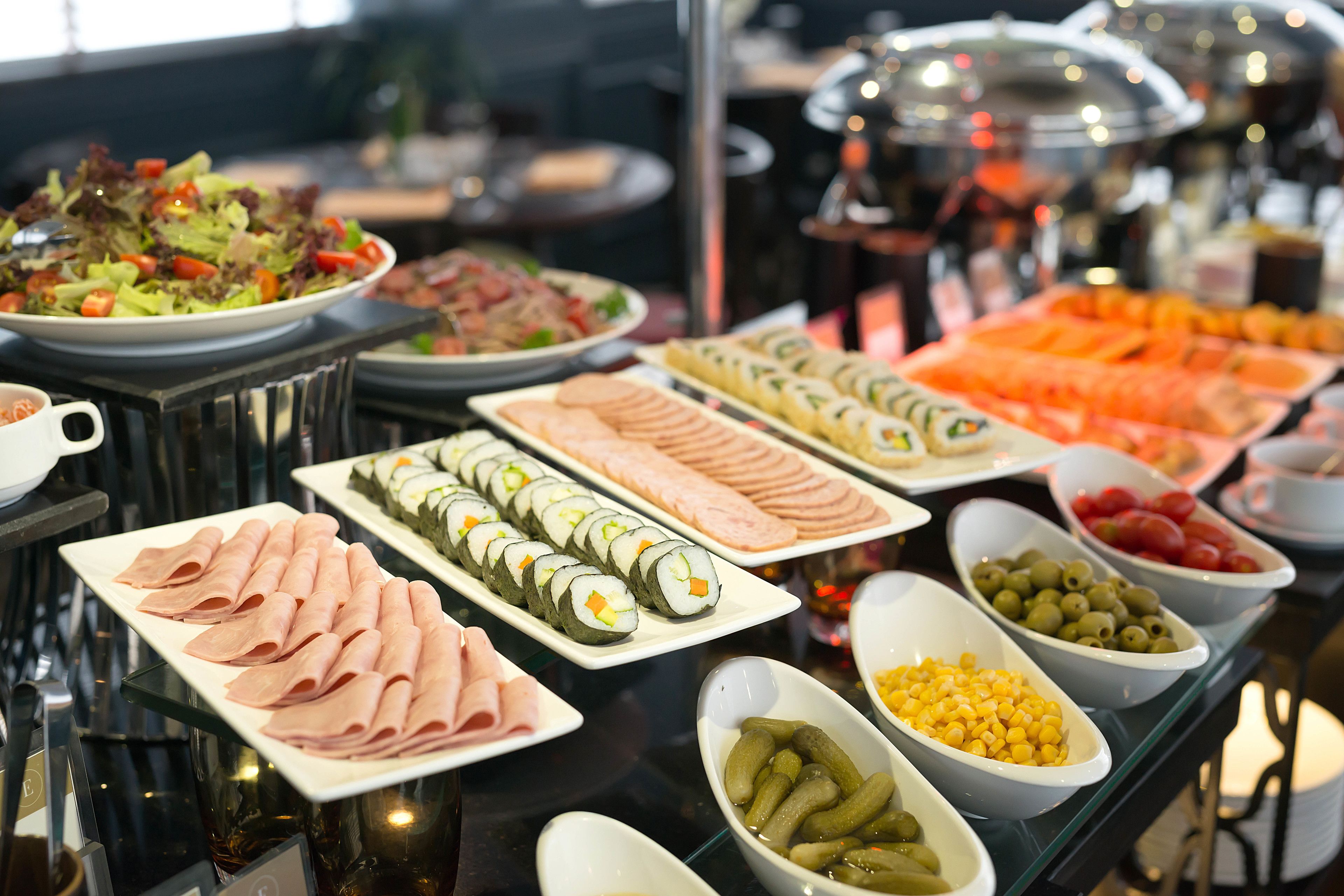 Un bufé con diversos alimentos, incluyendo sushi, carnes y verduras.