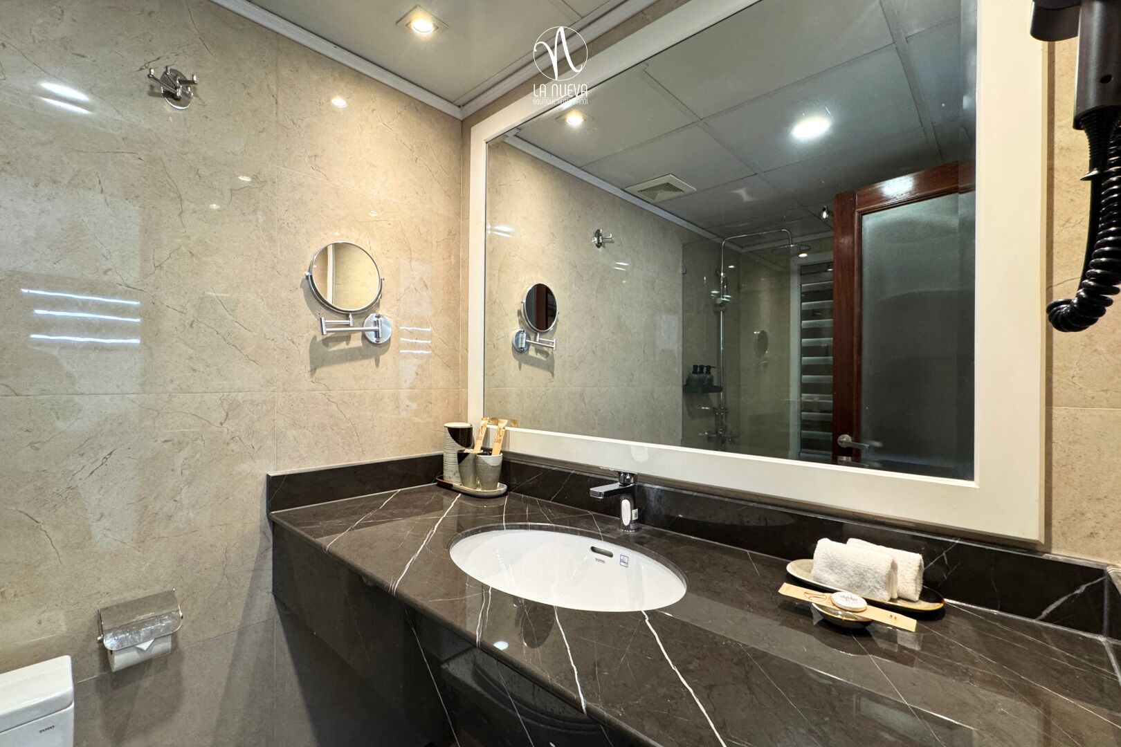 A modern bathroom with a large mirror, a sink, and a shower area.