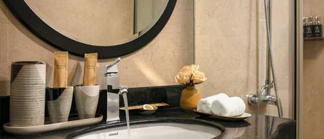 A bathroom with a sink, mirror, and shower.