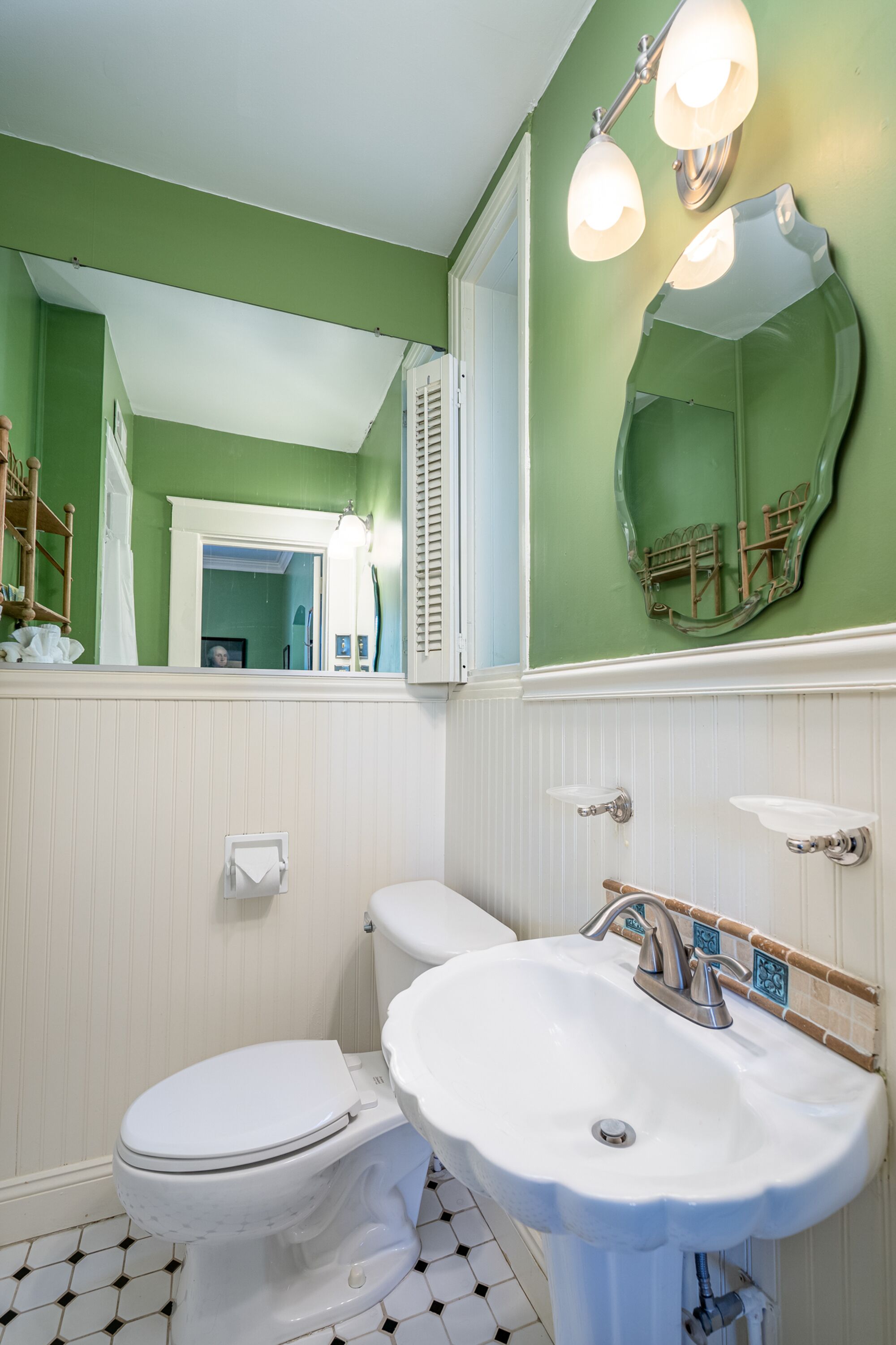 Un baño con un inodoro blanco, un lavabo blanco y una pared verde.