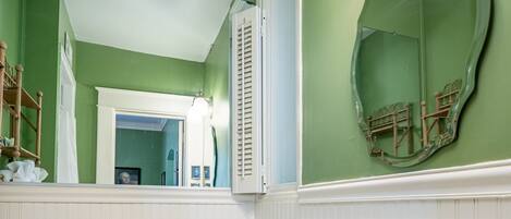 Un baño con un inodoro blanco, un lavabo blanco y una pared verde.