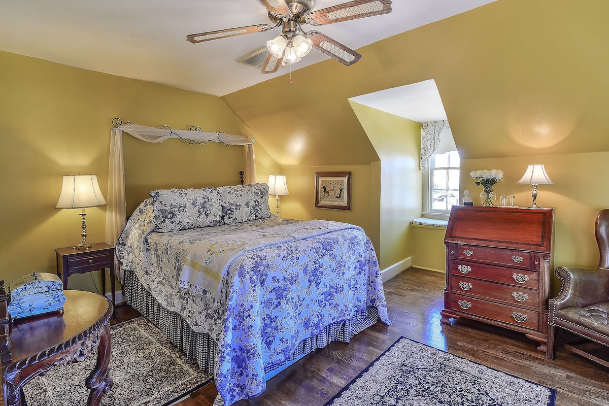 Une chambre à coucher avec un lit à baldaquin, une commode en bois et une chaise.
