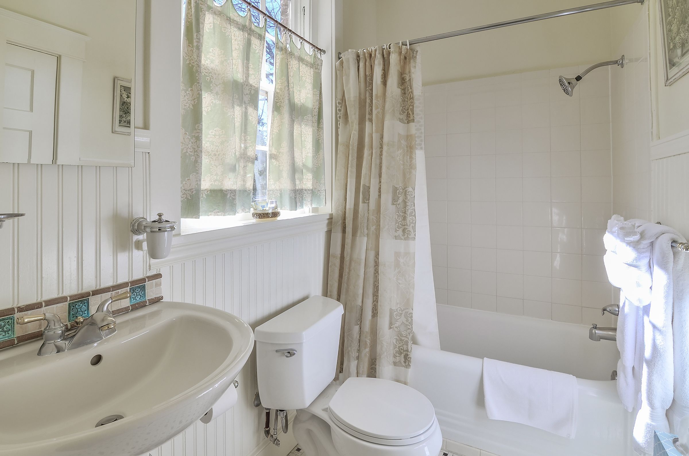 Une salle de bain avec un lavabo, des toilettes et une baignoire, le tout de couleur blanche.
