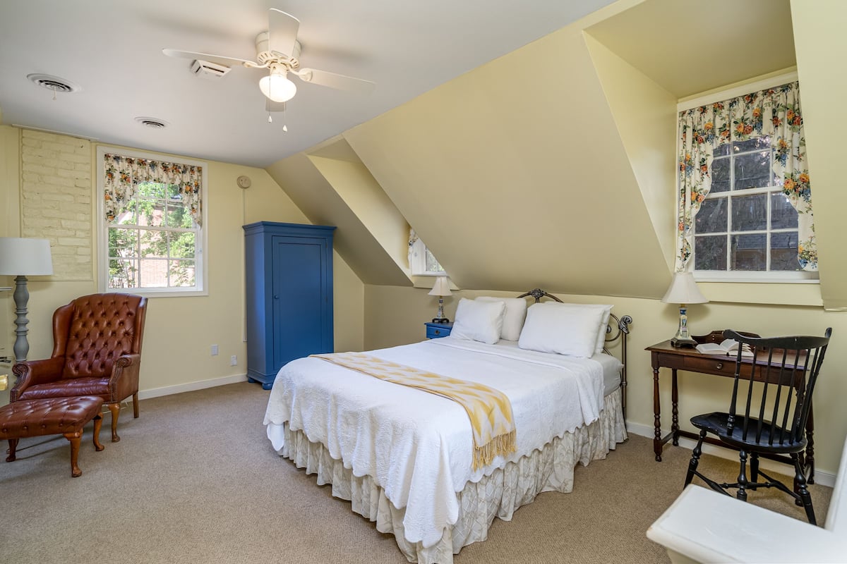 Une chambre à coucher avec un lit, une chaise, un bureau et une armoire.