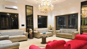 A spacious living room with beige sofas, a red sofa, and a central coffee table. - Hotel Supreme (Vasco) (Vasco da Gama)
