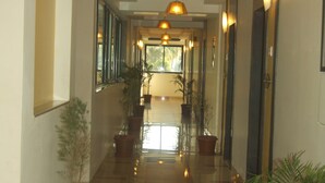 A corridor with potted plants, a ceiling light, and a door at the end. - Hotel Supreme (Vasco) (Vasco da Gama)