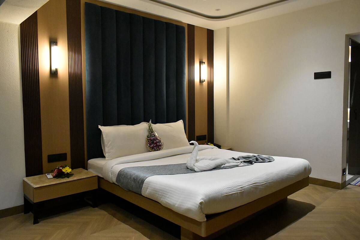 Una habitación de hotel moderna con una cama grande, paneles de madera y dos luces fijadas a la pared.