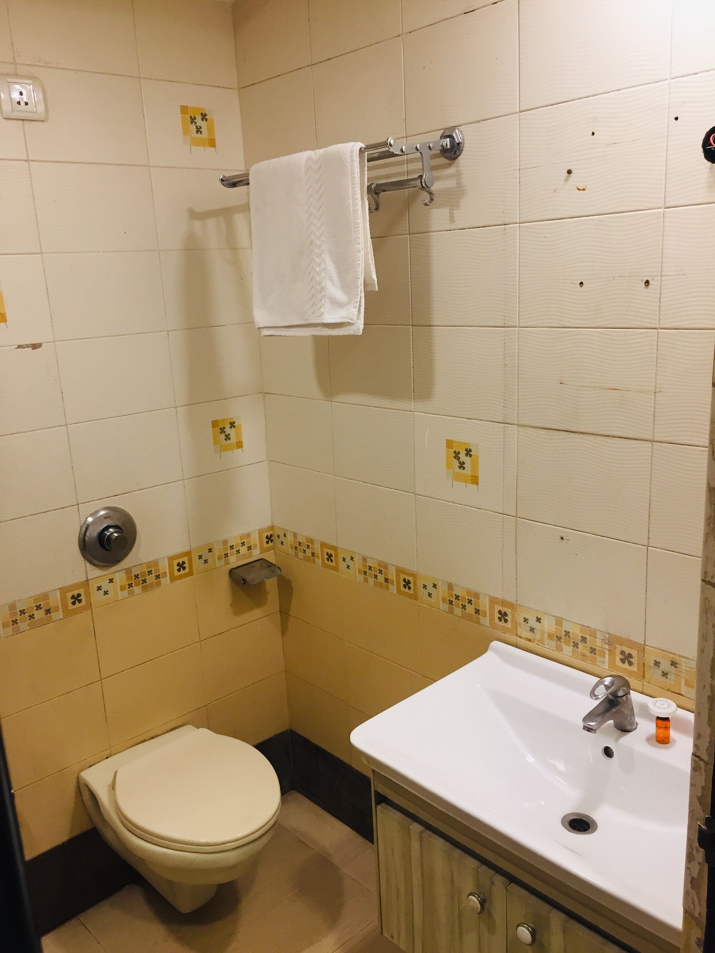 A small bathroom with a toilet, sink, and towel rack.