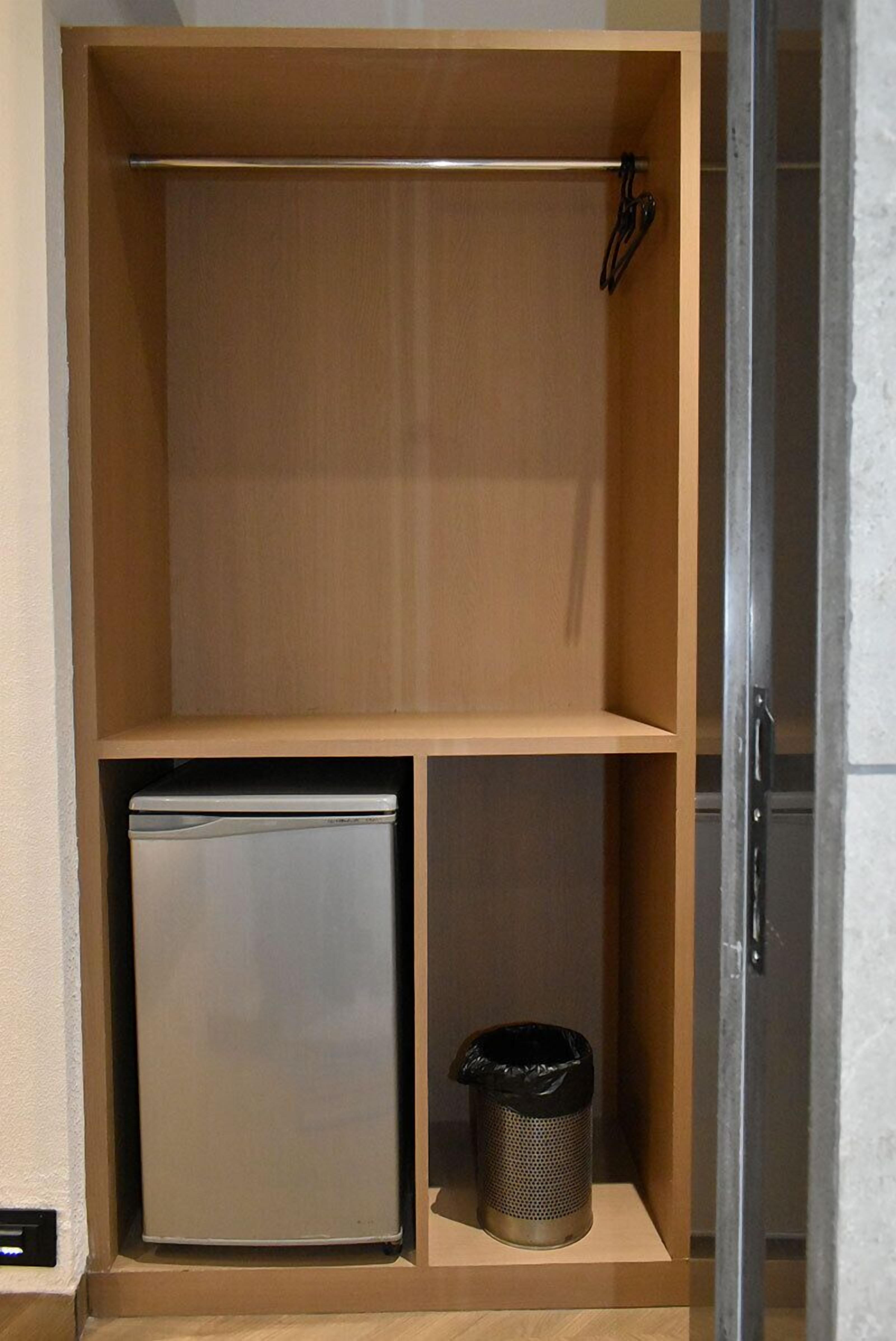 A compact storage unit with a small refrigerator and a waste bin.