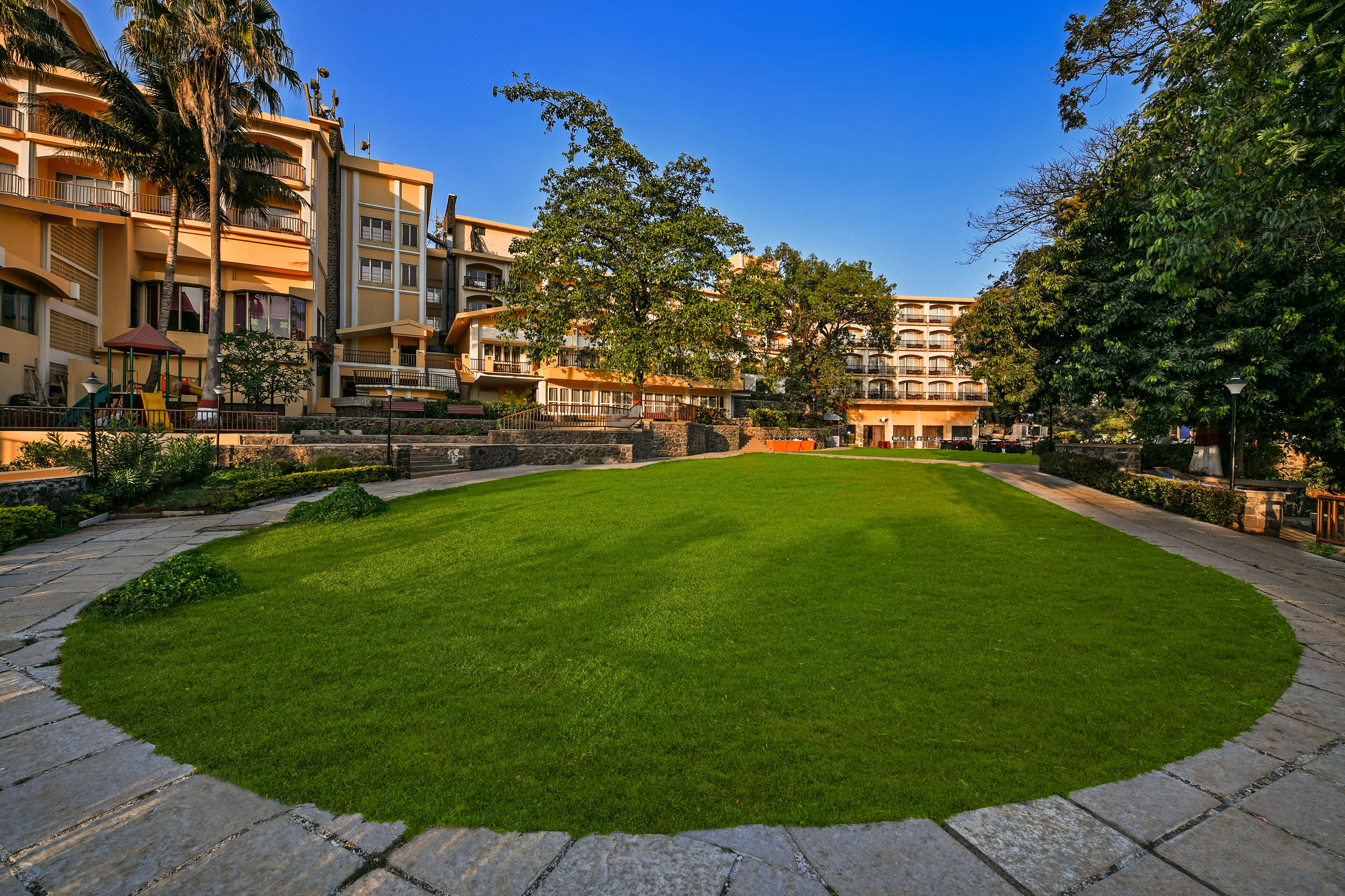 A courtyard with a well-maintained lawn, stone pathways, and multi-story buildings with balconies.