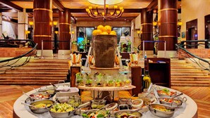 A buffet setup with various food stations, a central decorative structure, and a wooden interior. - Fariyas Resort Lonavala (Mawal)