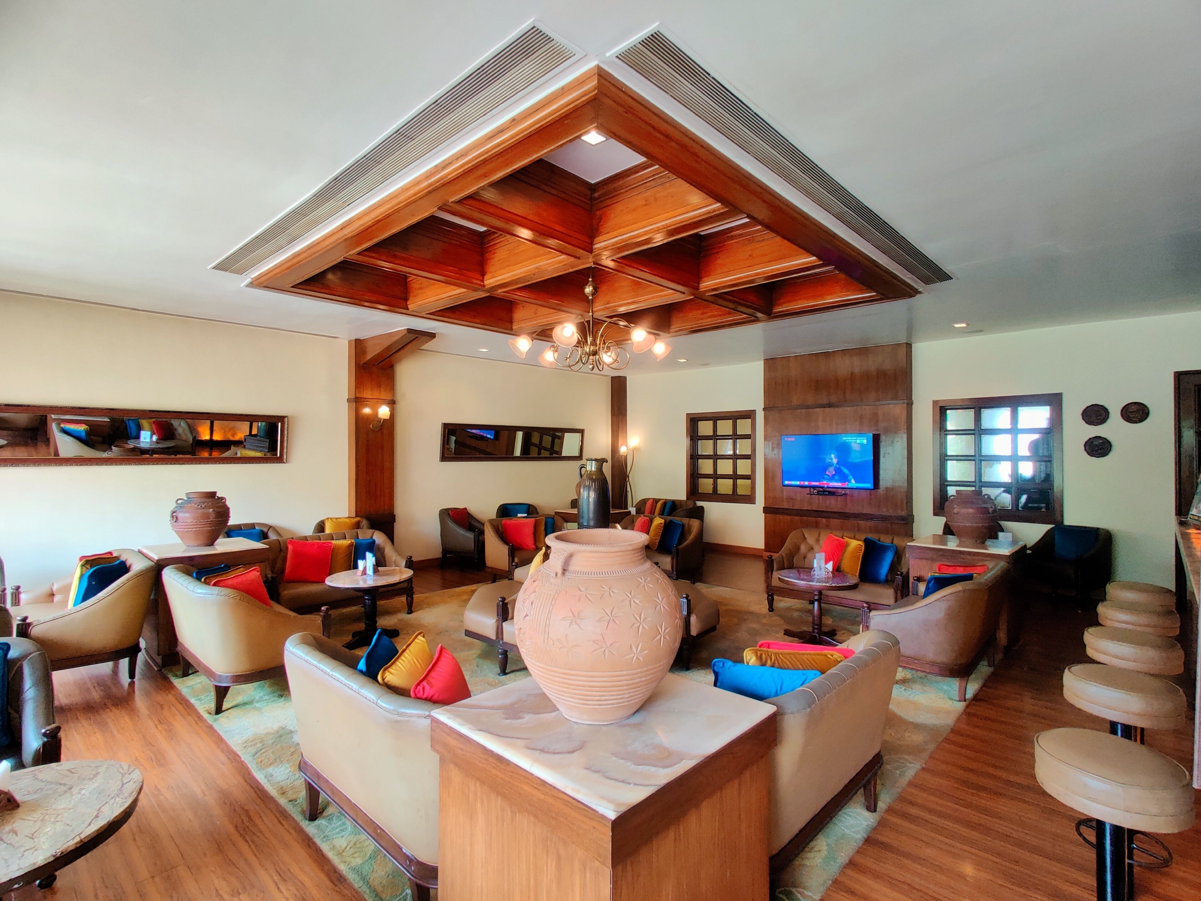 A spacious living area with multiple seating options, a large decorative vase, and a television mounted on the wall.