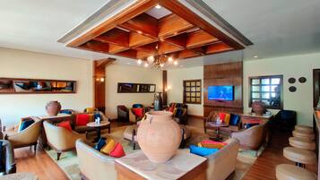 A spacious living area with multiple seating options, a large decorative vase, and a television mounted on the wall.