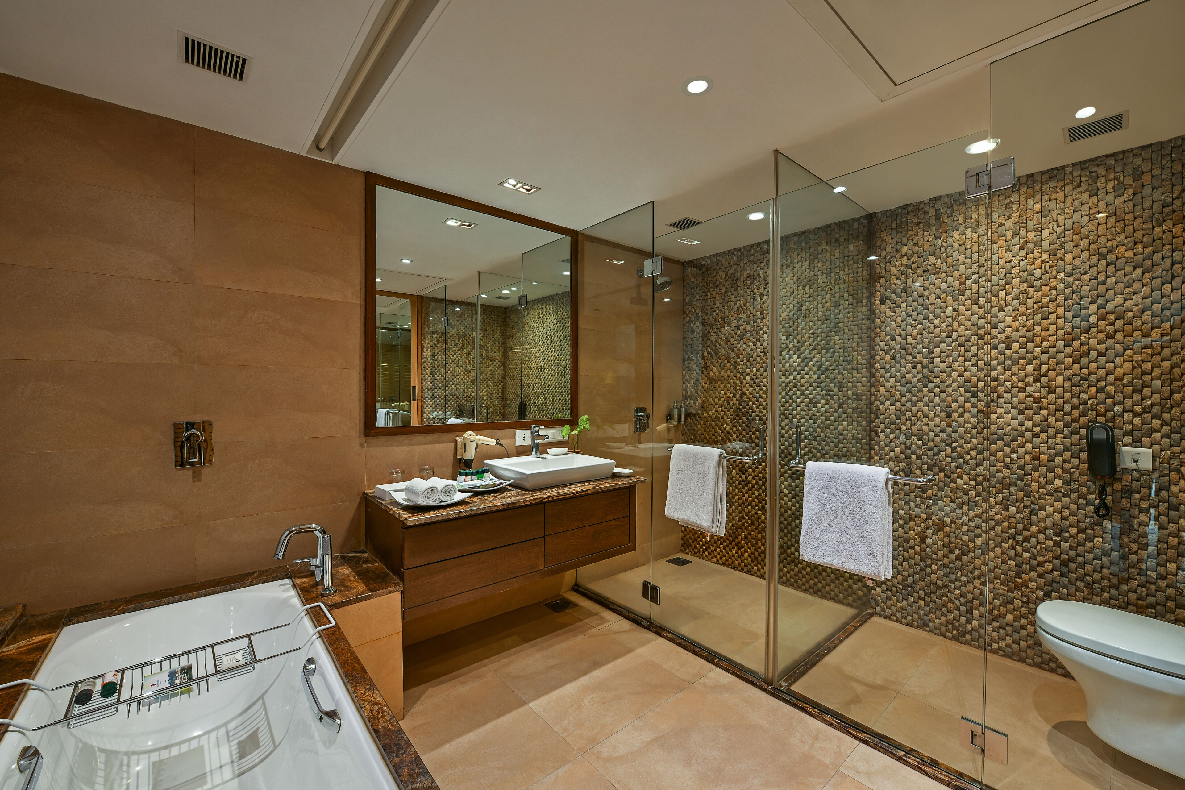 A modern bathroom with a glass-enclosed shower, a large mirror, and a vanity with a sink and towel rack.