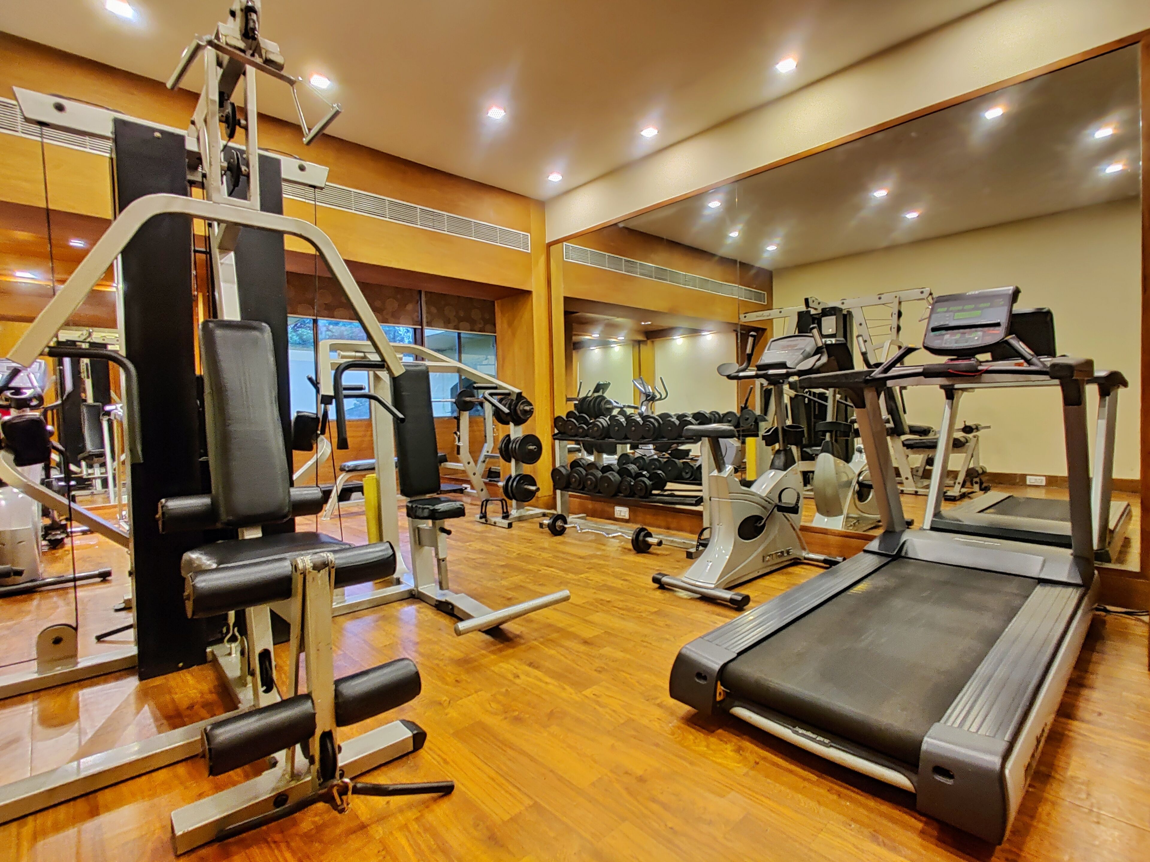 A gym with various exercise equipment, including a treadmill, weight machines, and dumbbells.