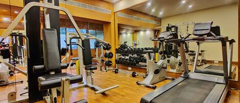 A gym with various exercise equipment, including a treadmill, weight machines, and dumbbells.