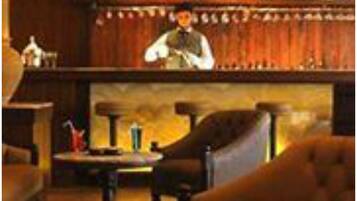 A bar area with a bartender, wooden bar counter, and seating.