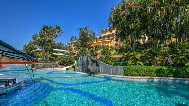 A hotel with a swimming pool, a water slide, and lush greenery. - Fariyas Resort Lonavala (Mawal)