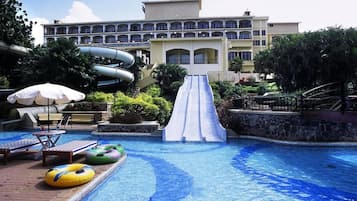 Relax by the pool with lounge chairs and umbrellas, surrounded by a hotel with spacious balconies.