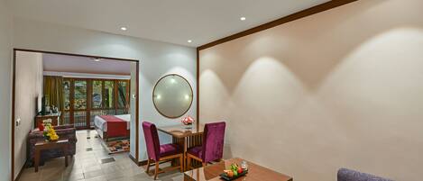 A modern hotel room with a dining area, a sofa, and a balcony with a view.