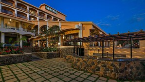 A hotel with a stone facade, multiple balconies, and a covered outdoor seating area. - Fariyas Resort Lonavala (Mawal)