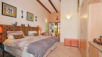 Quarto com cama grande, cabeceira de madeira, cômoda e mesa de cabeceira.