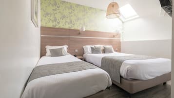 A modern bedroom with two beds, a wooden headboard, a skylight, and a hanging light fixture.