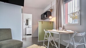 A compact living space with a dining area, kitchenette, and a seating area. - The Originals City, Hôtel Le Beaujoire, Nantes (Nantes)