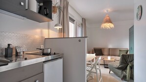 A modern kitchen with a built-in stove, a refrigerator, and a hanging light fixture. - The Originals City, Hôtel Le Beaujoire, Nantes (Nantes)