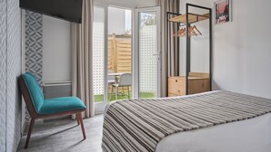 A bedroom with a bed, a chair, a wardrobe, and a sliding glass door leading to an outdoor area. - The Originals City, Hôtel Le Beaujoire, Nantes (Nantes)