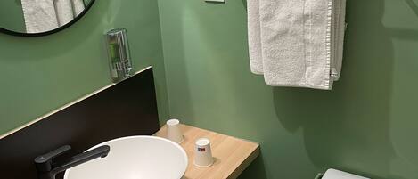 A bathroom with a round mirror, a white sink, a toilet, and a towel rack.