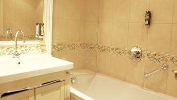 A bathroom with a sink, mirror, and bathtub.