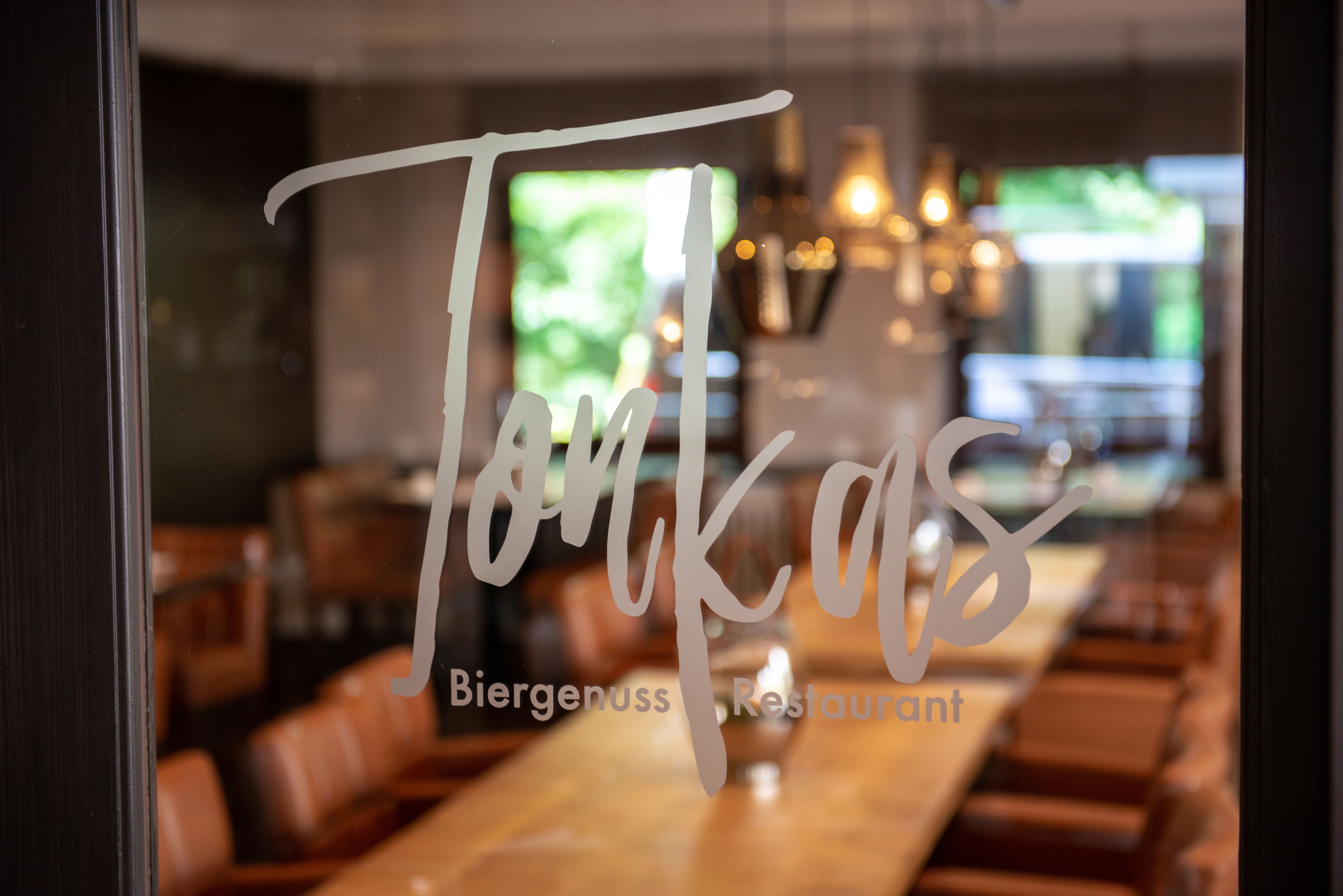 En restauranginteriör med ett långt träbord och bruna läderstolar.