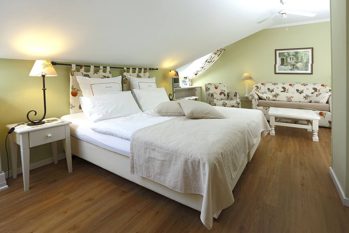 A bedroom with a bed, bedside tables, a lamp, a chair, and a ceiling fan.