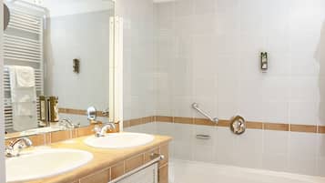 Une salle de bain avec deux lavabos, une baignoire et un grand miroir.
