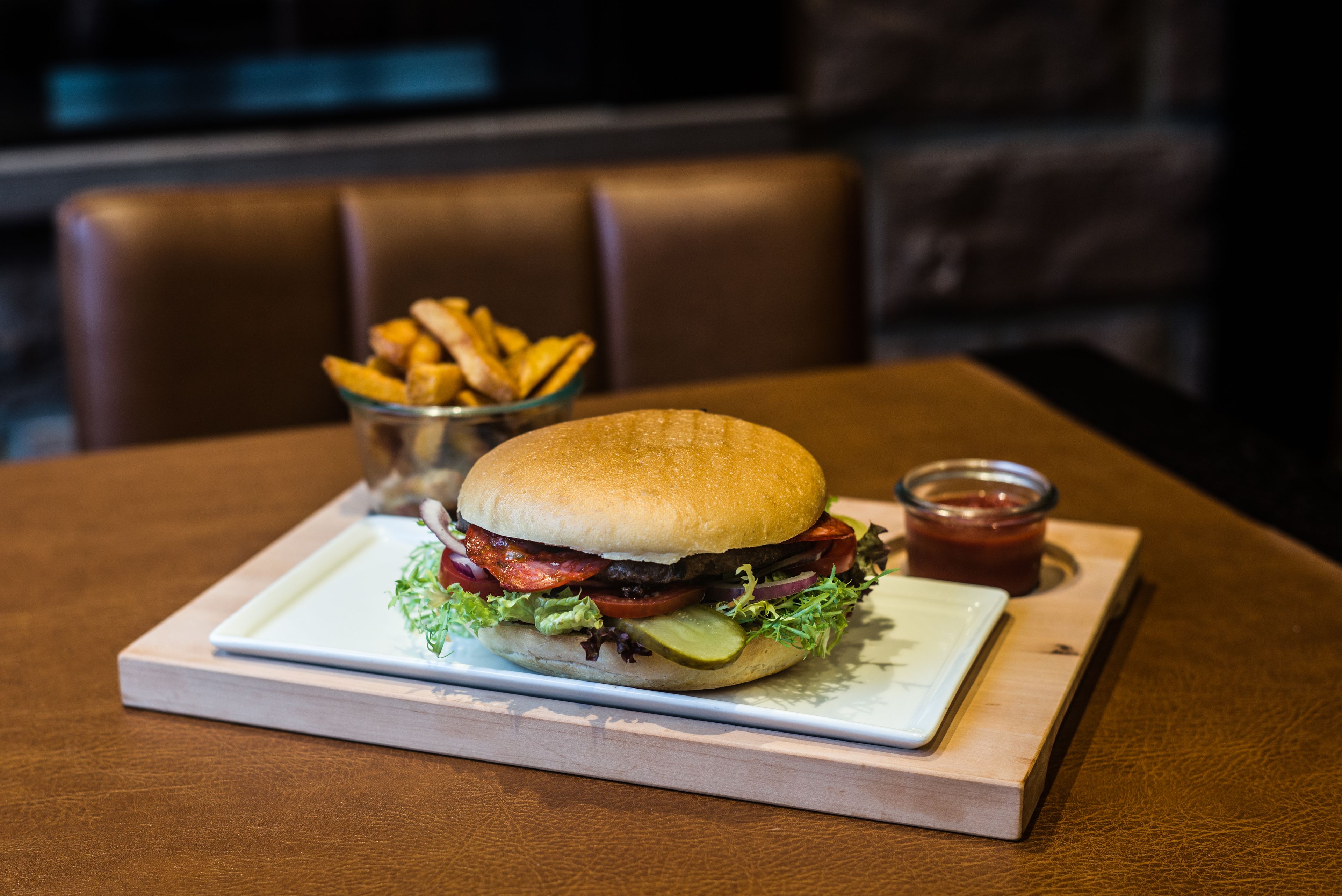 Una hamburguesa con papas fritas y kétchup sobre una mesa de madera.