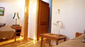 A bedroom with a wooden bed, a nightstand with a lamp, a door, and an air conditioning unit. - Kolory Guest House (Kraków)