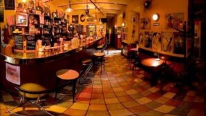 A bar with a checkered floor, bar stools, and hanging lights. - Kolory Guest House (Kraków)