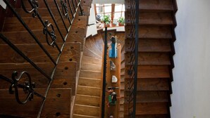 A wooden staircase with metal railings, leading to a landing with potted plants and a small table with tools. - Kolory Guest House (Kraków)