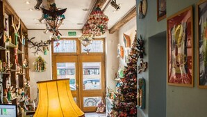 A warmly lit interior with a Christmas tree, a lamp, and various decorations. - Kolory Guest House (Kraków)
