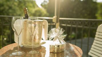Une table avec deux flûtes à champagne, une bouteille de champagne et une boîte cadeau, le tout sur un balcon.