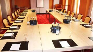 A conference room with long tables, chairs, and a whiteboard.