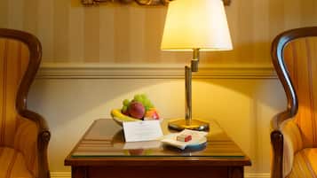 Ett hotellrum med ett bord dukat med frukt, en lampa och två vinglas.