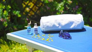 A table with a towel, a bottle, and a pair of sunglasses.
