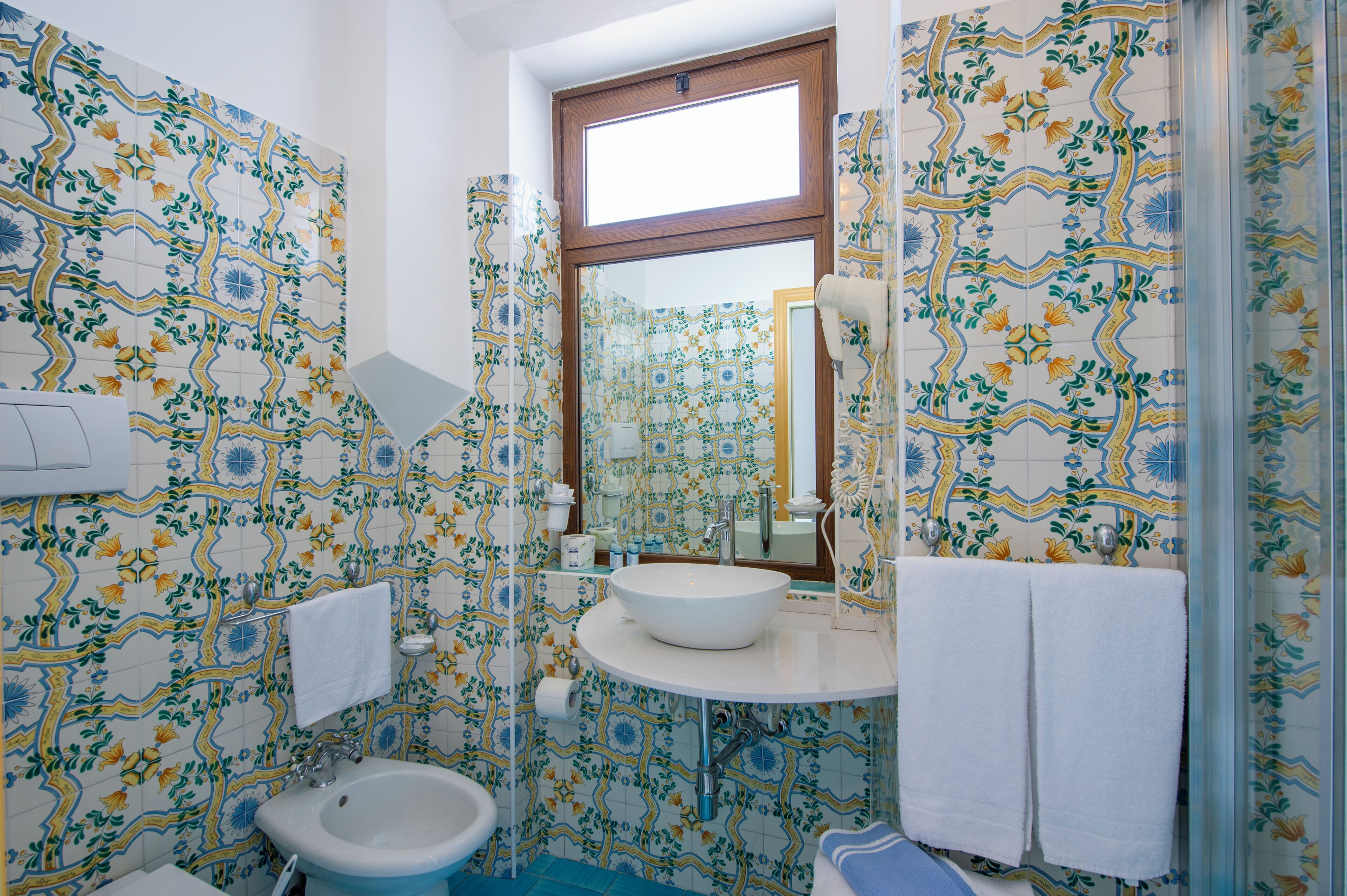 Un baño con lavamanos blanco, un espejo y una zona de ducha.