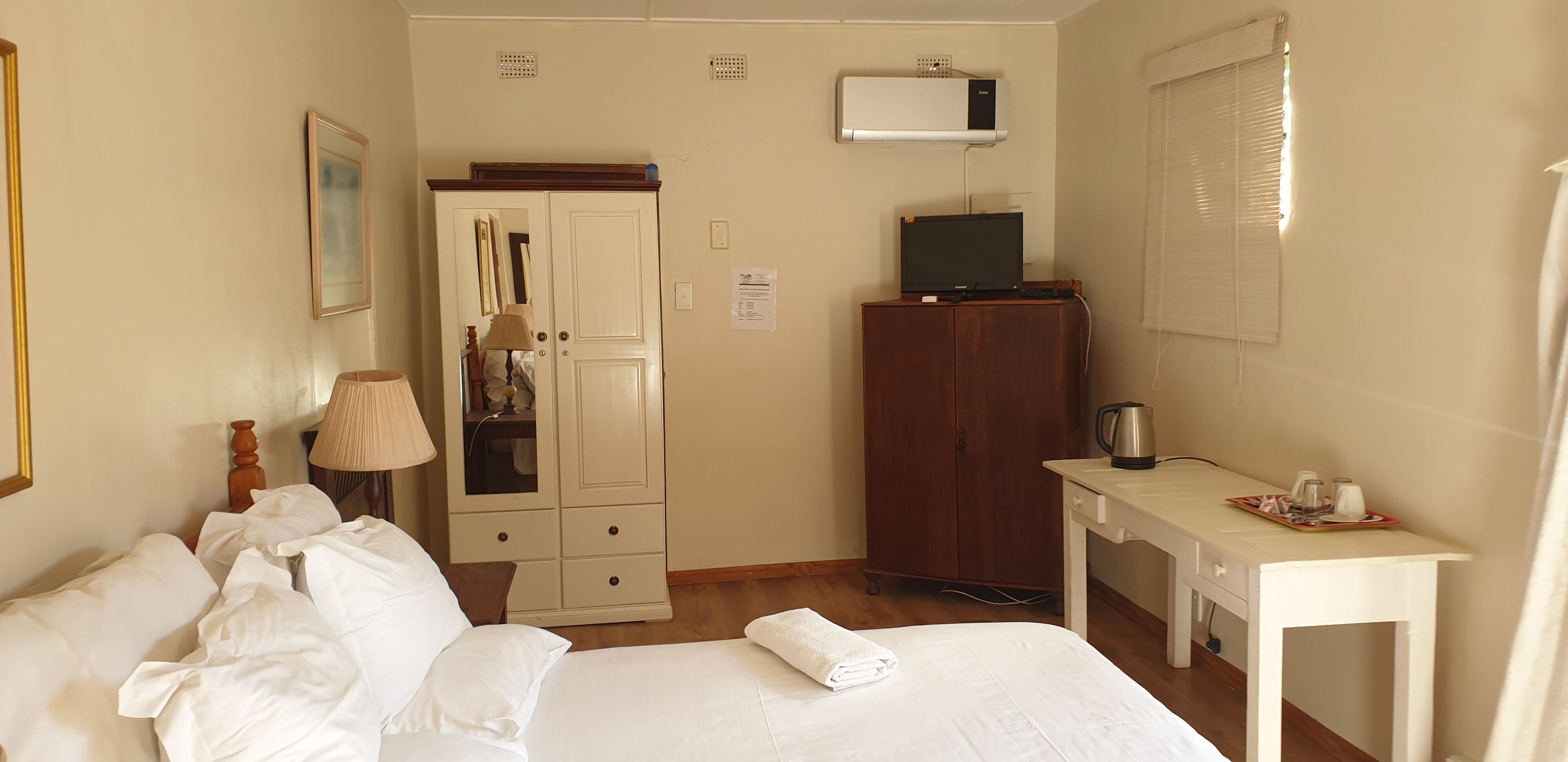 Habitación de hotel con cama, escritorio, armario y televisor.