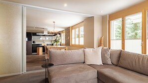 Un soggiorno moderno con un divano modulare beige, un tavolo da pranzo con sedie e una cucina sullo sfondo.