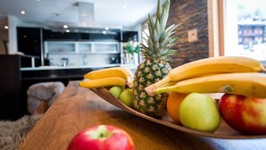 Un tavolo di legno con una ciotola di frutta contenente banane, mele e un'ananas.